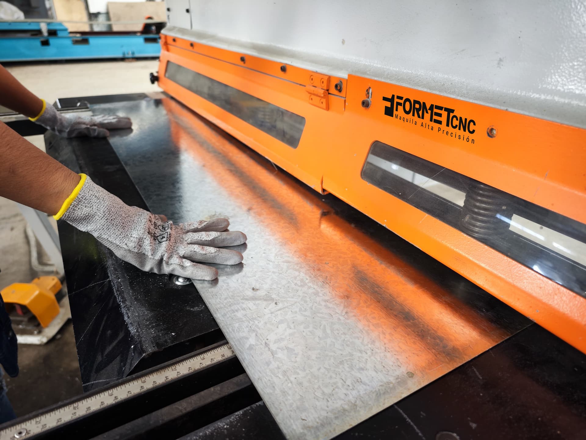 Operario manejando una guillotina CNC, garantizando cortes rectos y limpios en láminas metálicas para proyectos industriales robustos.