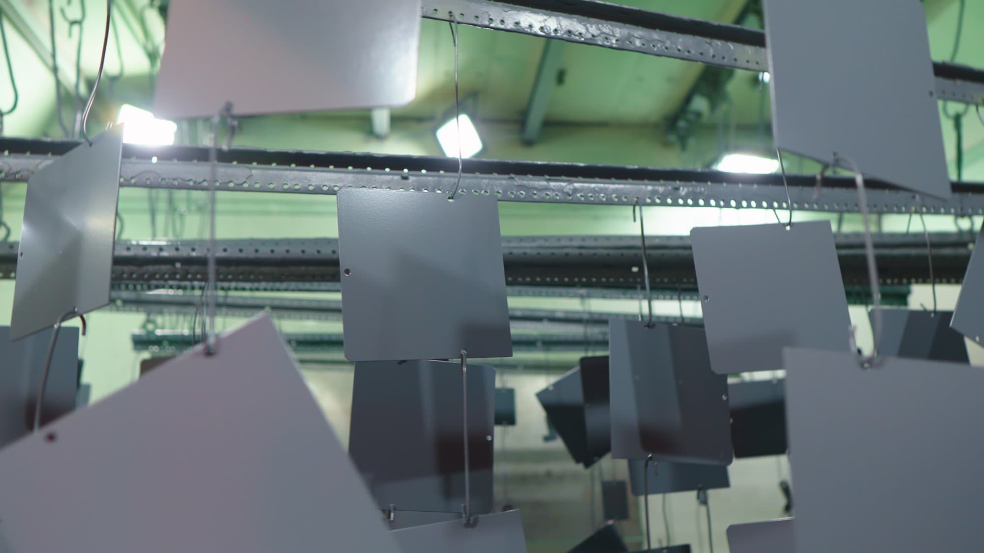 Piezas metálicas recubiertas colgadas en la línea de pintura electrostática, Formet CNC